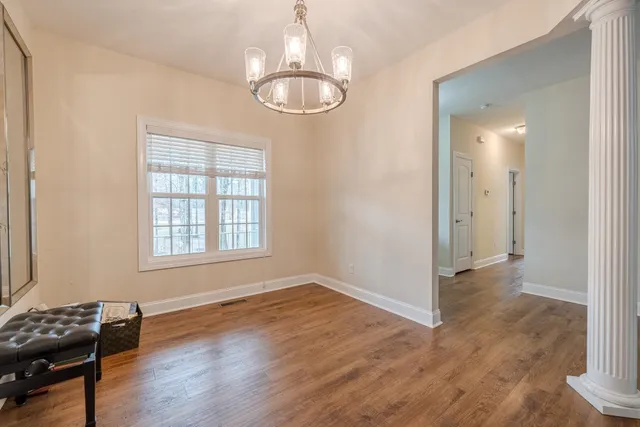 an empty room with wooden floor mirror and windows