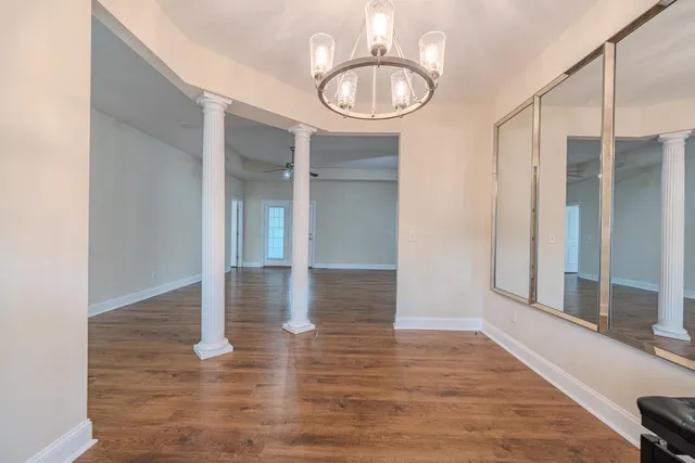 an empty room with wooden floor mirror and windows