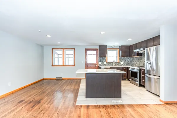 a large kitchen with kitchen island a large counter top space stainless steel appliances and windows