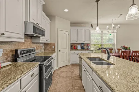 a kitchen with stainless steel appliances granite countertop a sink a stove and a refrigerator