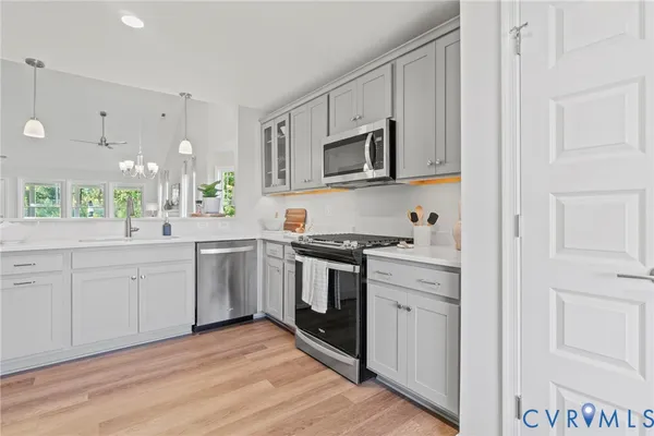 a kitchen with stainless steel appliances granite countertop white cabinets a sink a stove a window and white