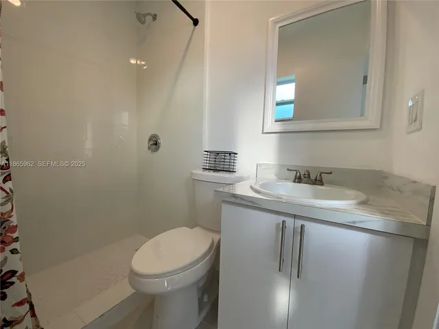 a bathroom with a granite countertop sink a toilet and mirror