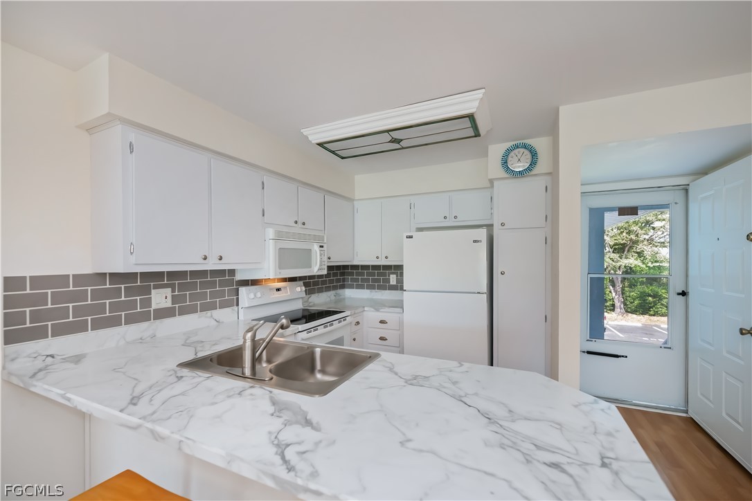 1100 Pondella Road, Unit 514 Cape Coral, FL 33909 - Photo 7 of 34 a kitchen with a refrigerator a stove and white cabinets with wooden floor