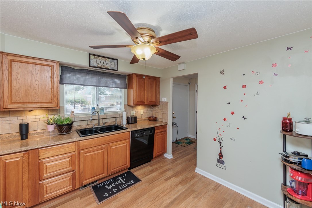 6476 State Road, Unit H8 Cleveland, OH 44134 - Photo 10 of 35 Kitchen featuring black dishwasher, brown cabinets, light countertops, backsplash, light hardwood floors, and ceiling fan