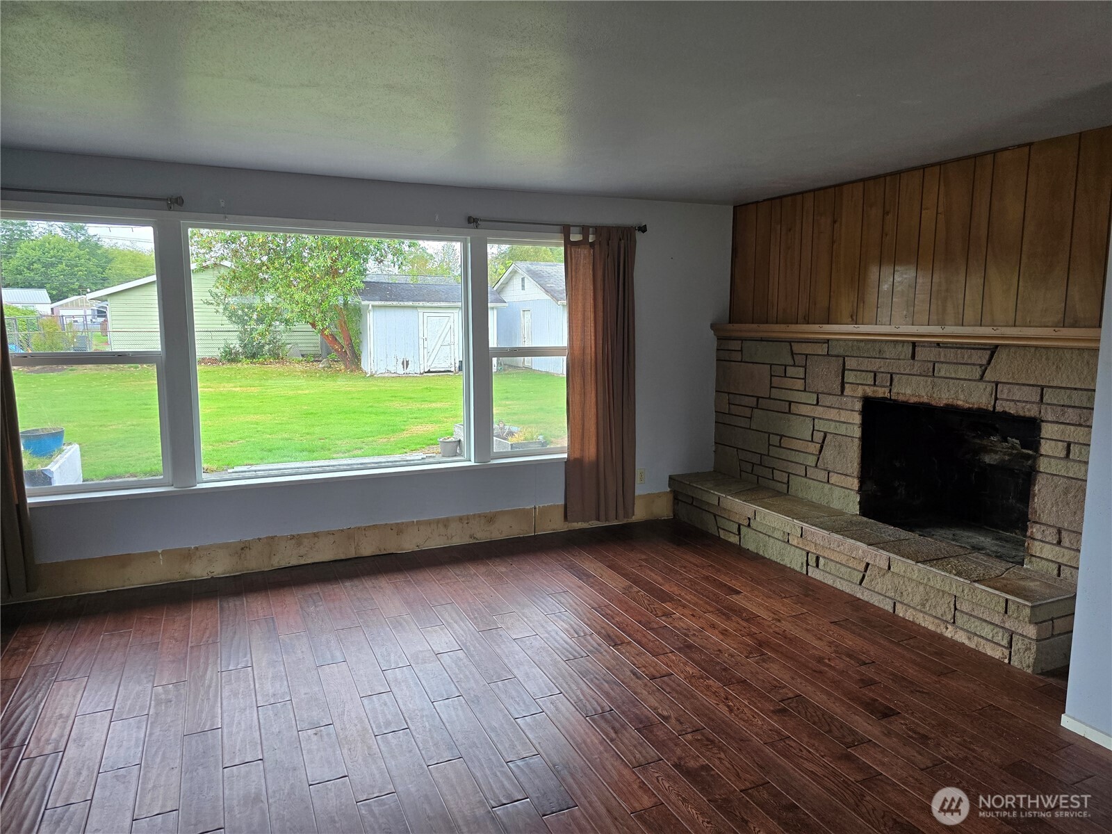 711 F Street Forks, WA 98331 - Photo 12 of 26 an empty room with wooden floor fireplace and windows