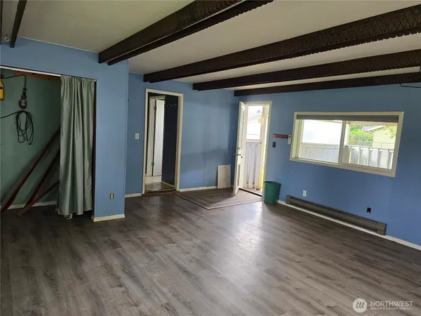 a view of an empty room with wooden floor and a window
