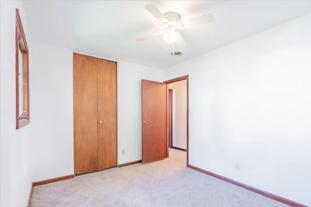 an empty room with a window and a fan