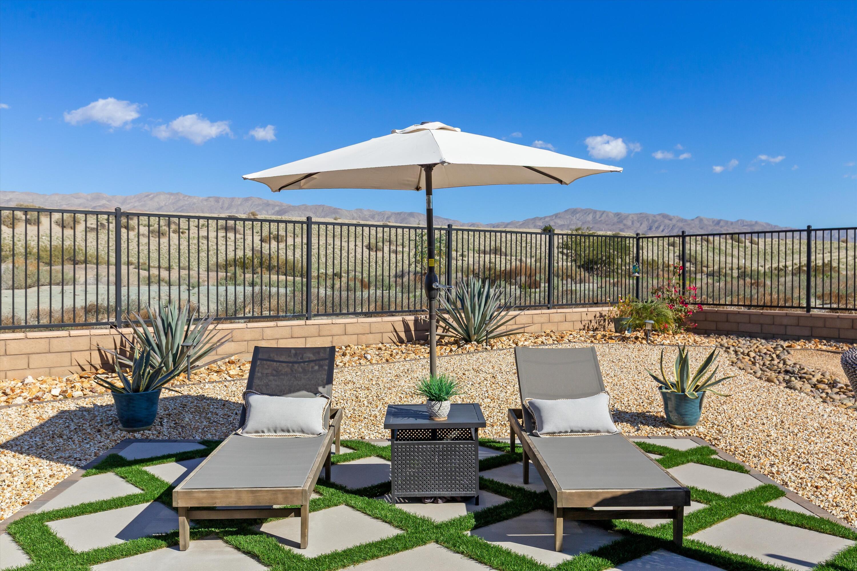 42940 Ascona Lane Indio, CA 92203 - Photo 22 of 36 a view of a patio with couches table and chairs under an umbrella