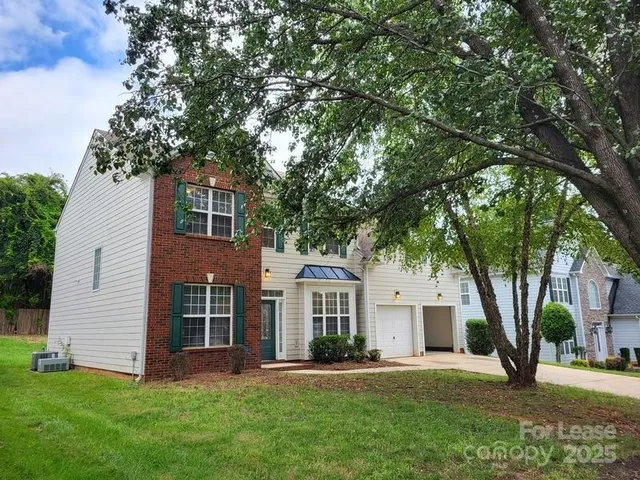 a front view of a house with a garden and trees