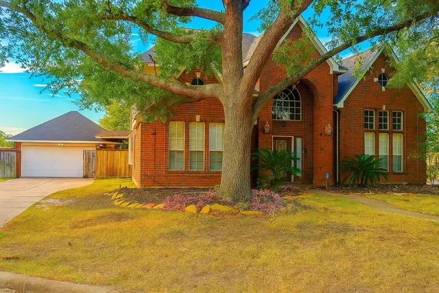 a view of yellow house with a large tree and a big yard