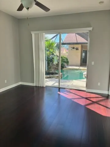 a view of empty room with wooden floor and fan