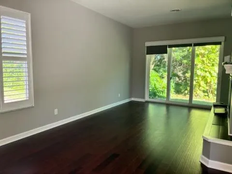 an empty room with wooden floor and windows with lake view