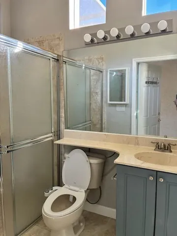 a bathroom with a granite countertop toilet sink and mirror