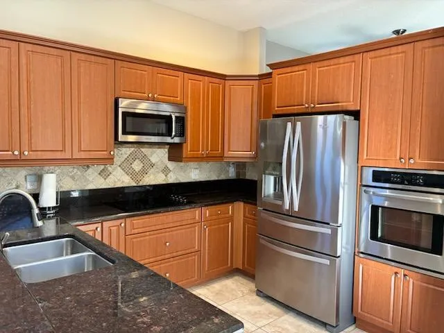 a kitchen with granite countertop a refrigerator and microwave