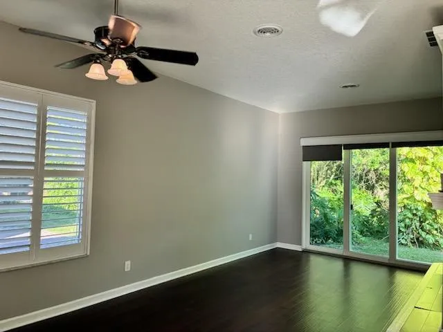 a view of empty room with wooden floor and fan