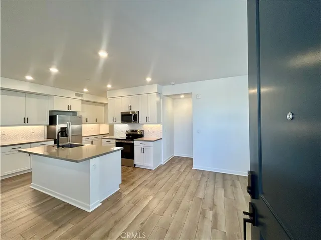 a large kitchen with stainless steel appliances kitchen island a large counter top and a wooden floors