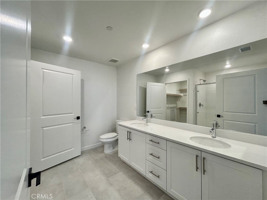 6114 Valentina Way, Unit 101 Eastvale, CA 92880 - Photo 10 of 23 a spacious bathroom with a double vanity sink mirror and toilet