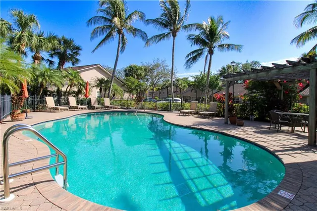 a view of a swimming pool with a lawn chairs under palm trees