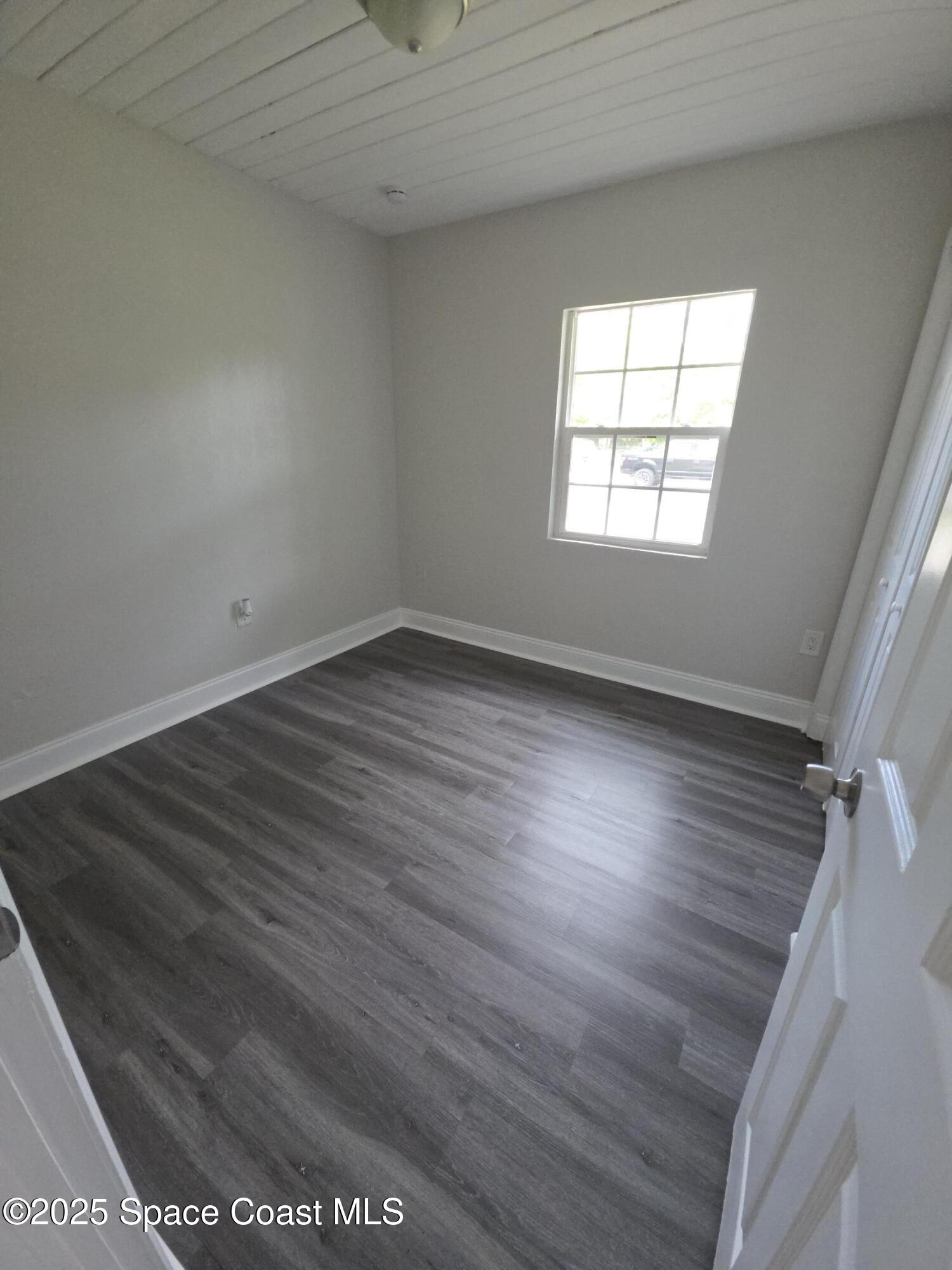 413 Dove Avenue Rockledge, FL 32955 - Photo 8 of 10 an empty room with wooden floor and windows