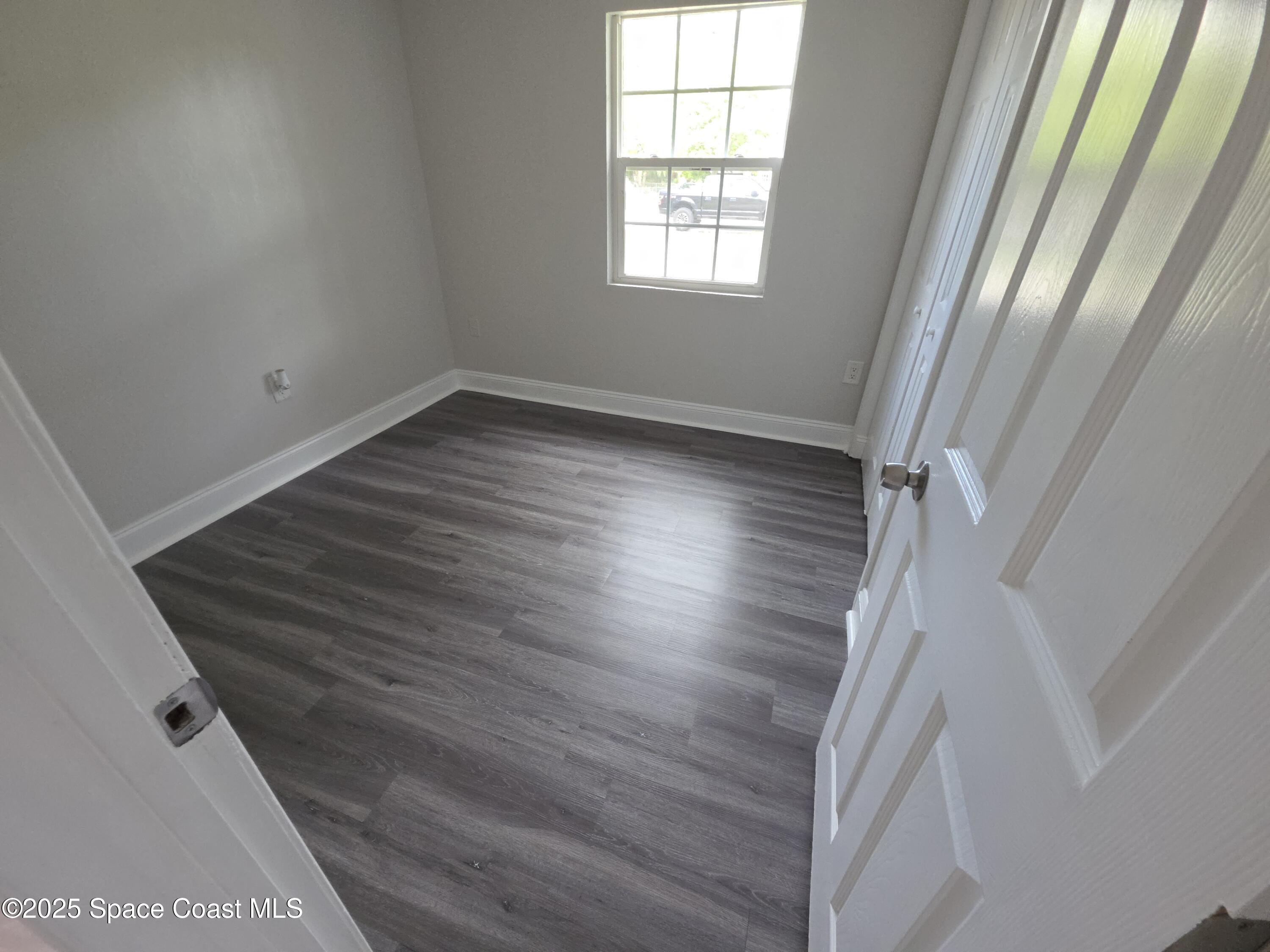 413 Dove Avenue Rockledge, FL 32955 - Photo 9 of 10 an empty room with wooden floor and windows