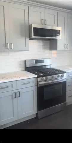 a kitchen with granite countertop white cabinets and stainless steel appliances