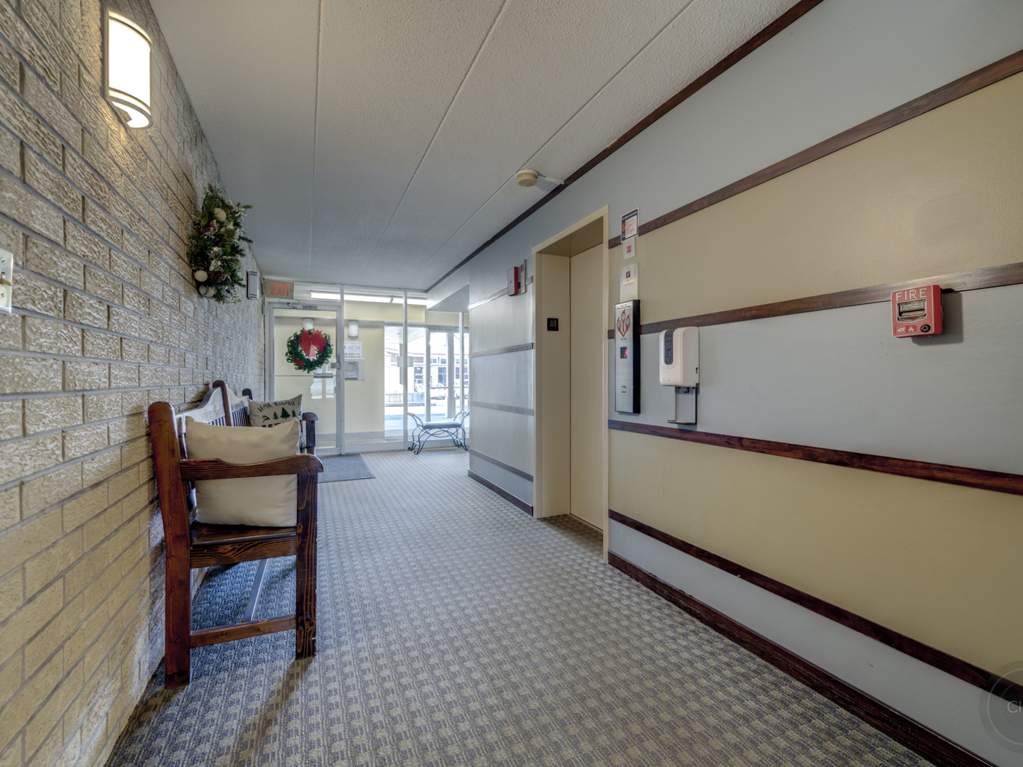 100 West Butterfield Road, Unit 405N Elmhurst, IL 60126 - Photo 4 of 27 a hallway with a chair and a potted plant on a dresser