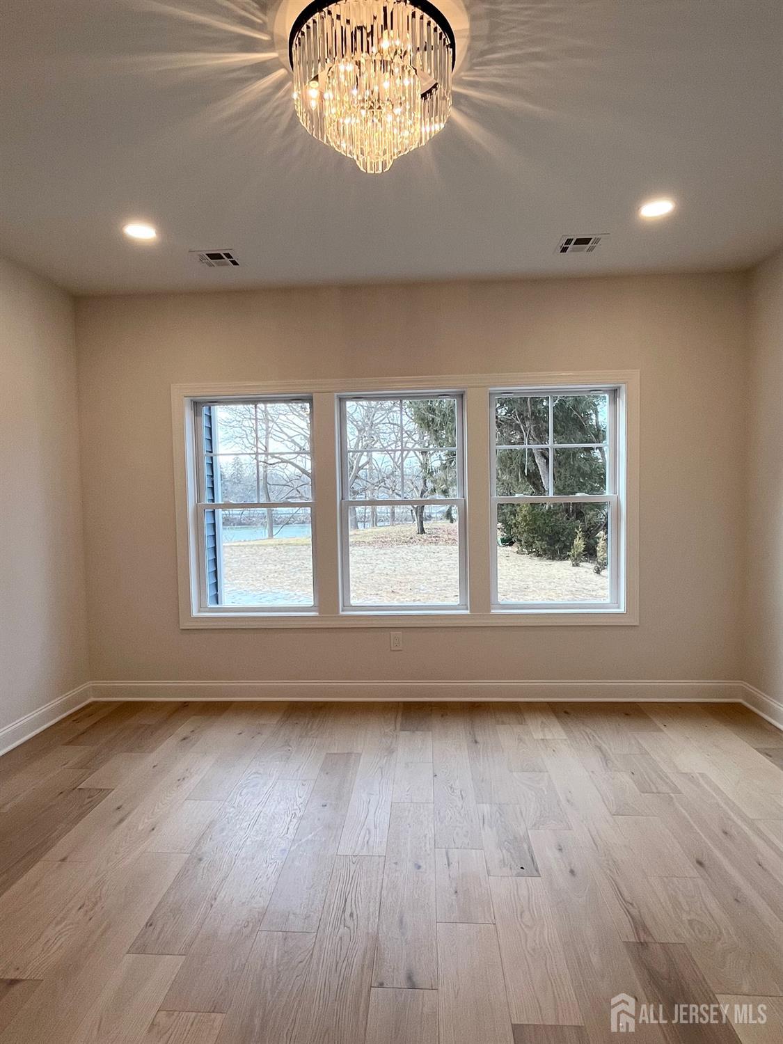 10 Johnson Avenue Matawan, NJ 07747 - Photo 7 of 26 an empty room with wooden floor chandelier and windows