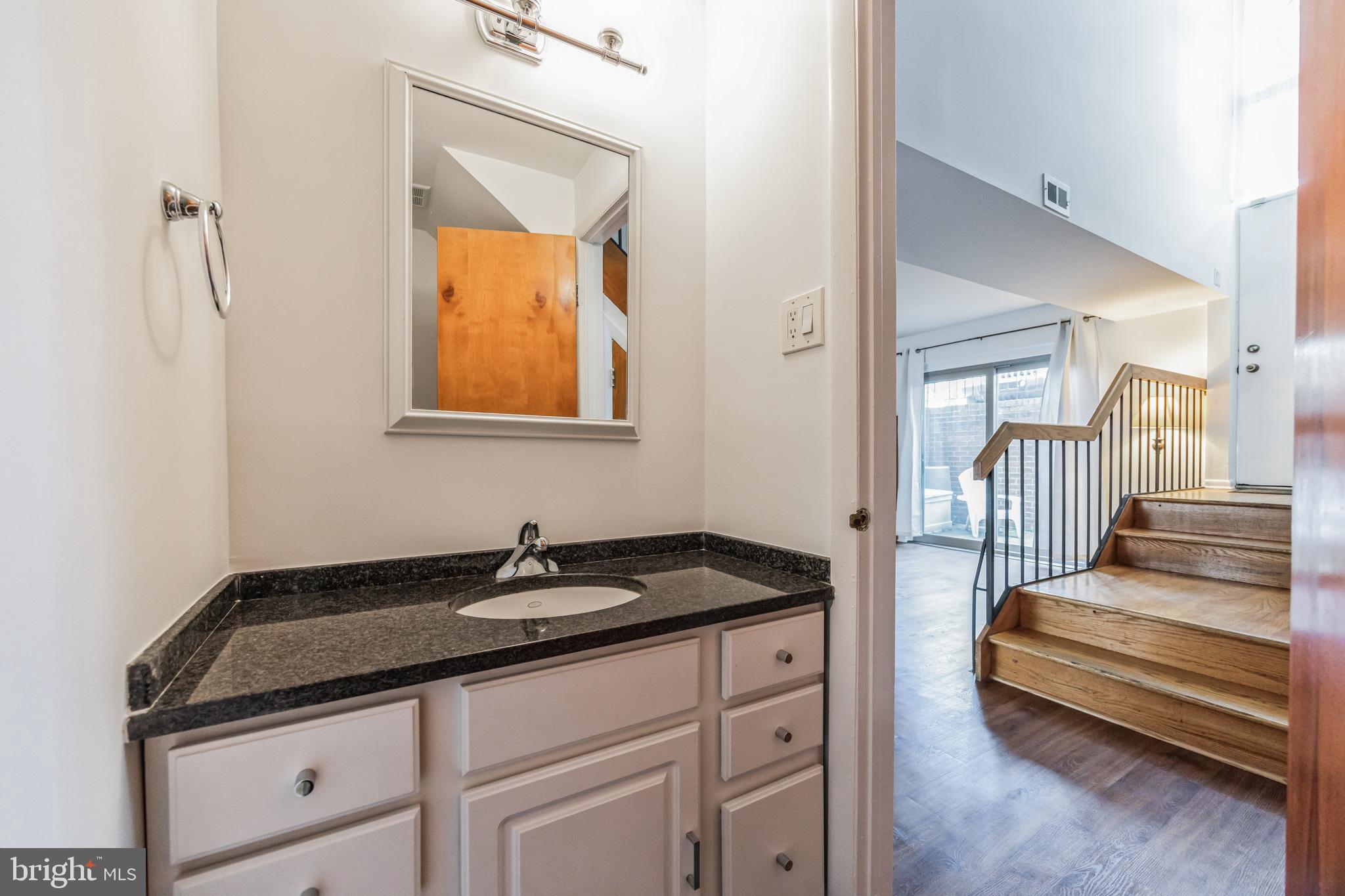 1928 Rodman Street, Unit A Philadelphia, PA 19146 - Photo 14 of 28 a bathroom with a granite countertop sink and a mirror