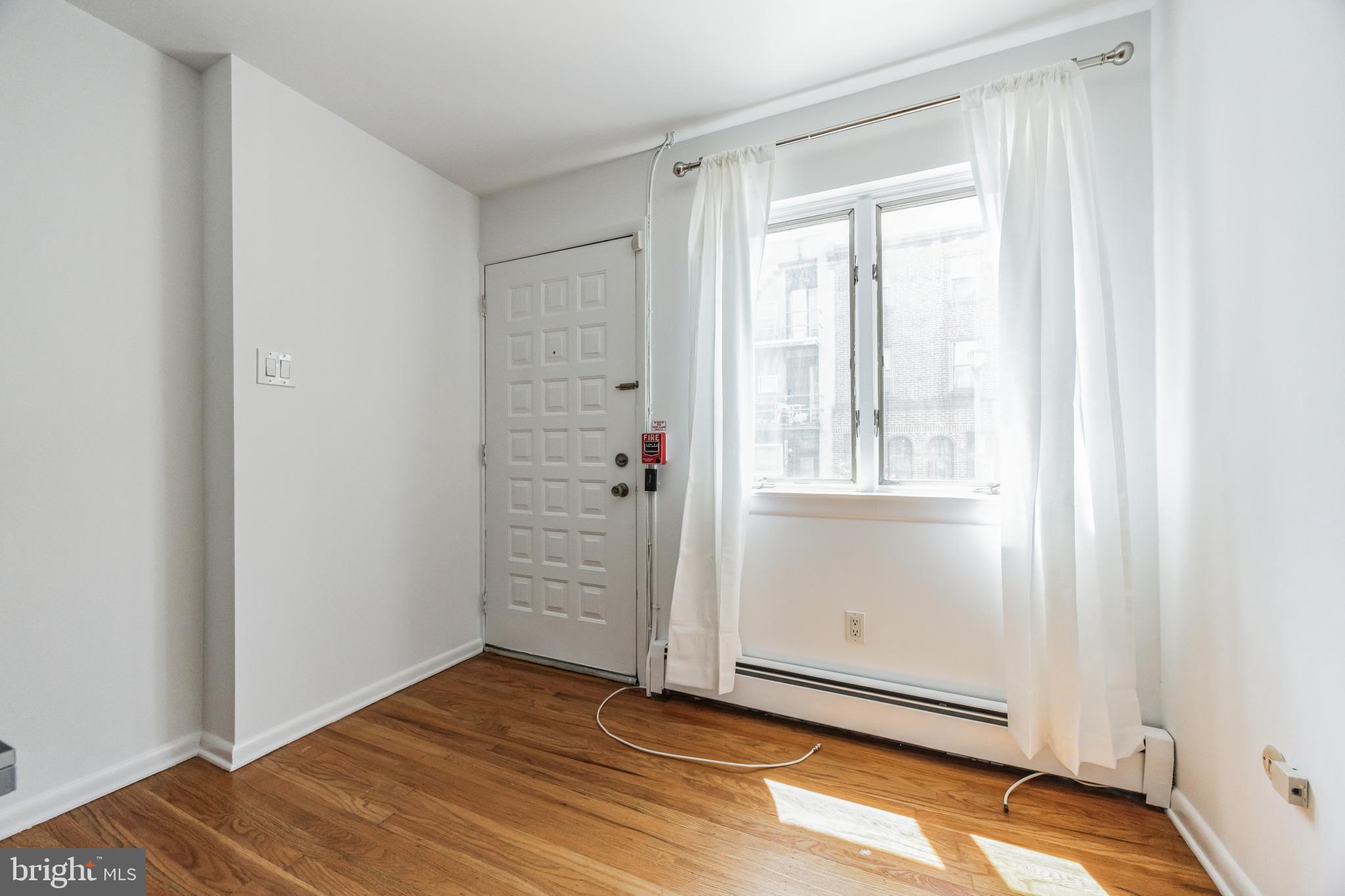 1928 Rodman Street, Unit A Philadelphia, PA 19146 - Photo 21 of 28 an empty room with wooden floor and windows