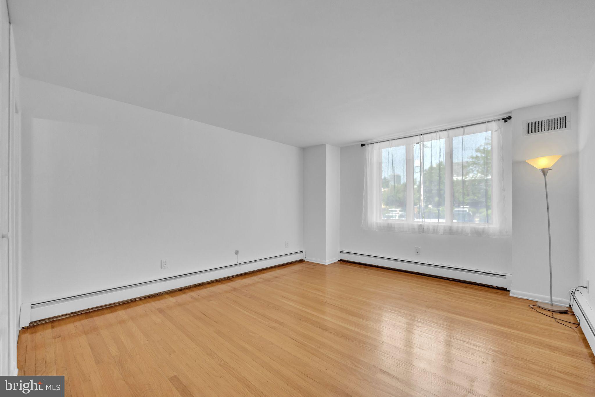 1928 Rodman Street, Unit A Philadelphia, PA 19146 - Photo 23 of 28 a view of an empty room with wooden floor and a window