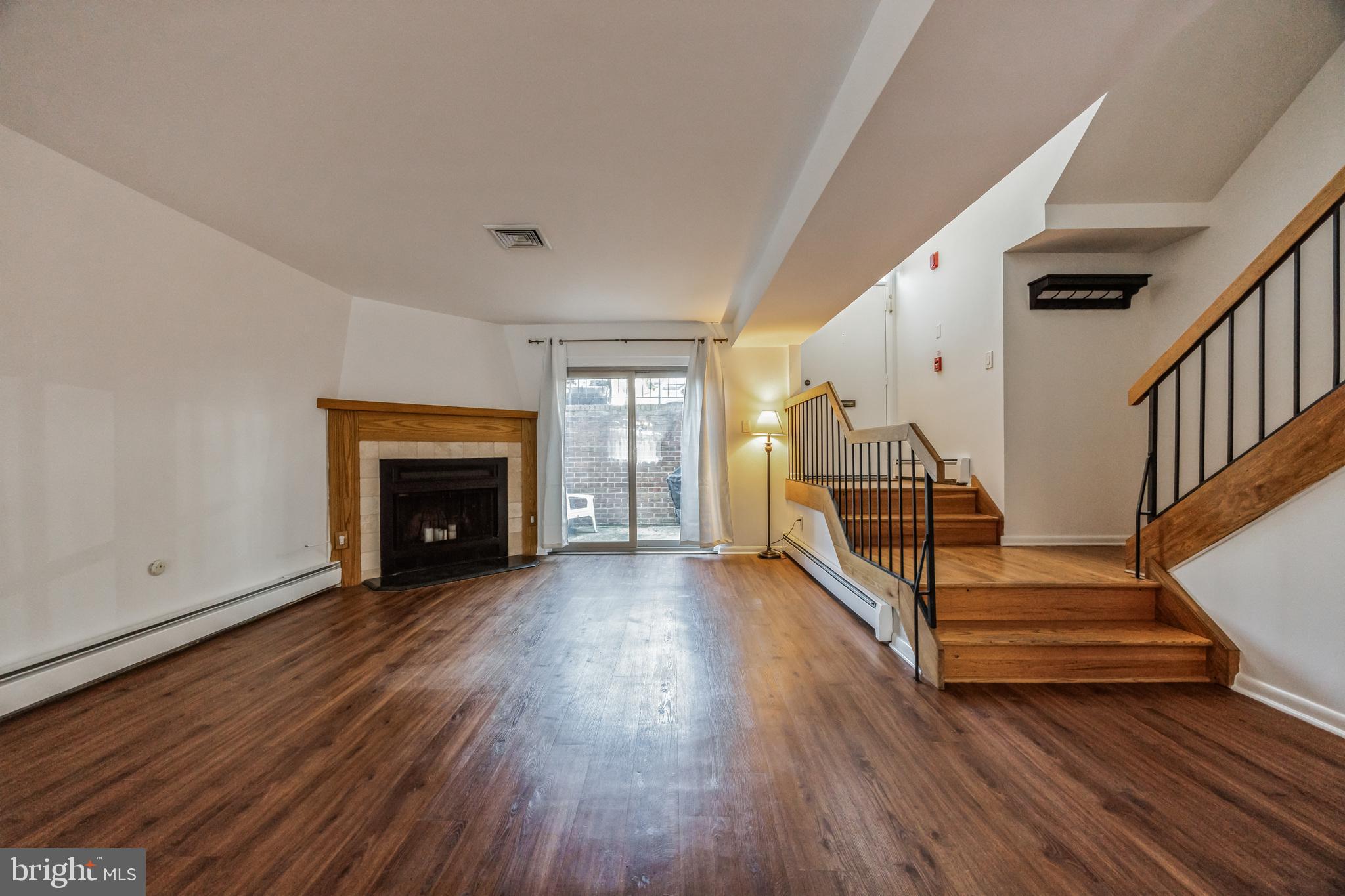 1928 Rodman Street, Unit A Philadelphia, PA 19146 - Photo 3 of 28 a view of an empty room with wooden floor fireplace and a window
