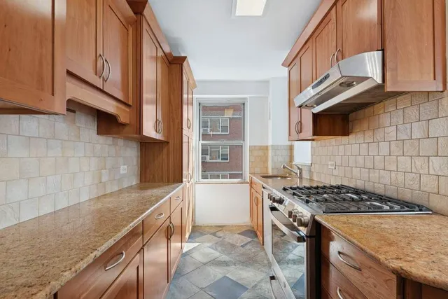 a kitchen with stainless steel appliances granite countertop a refrigerator a stove and a sink