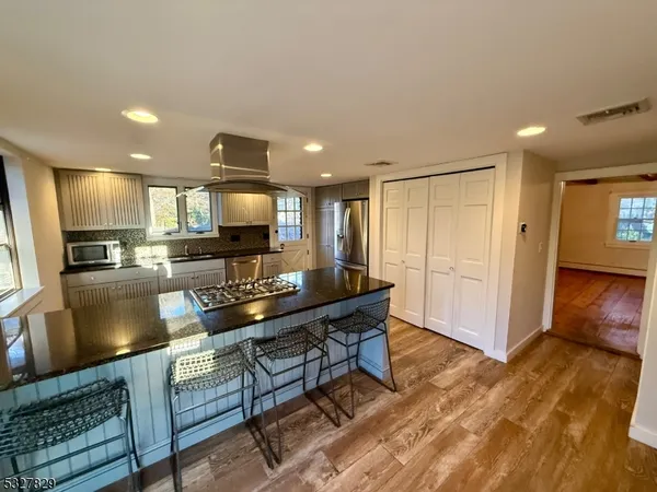 a living room with stainless steel appliances kitchen island granite countertop furniture and a wooden floor