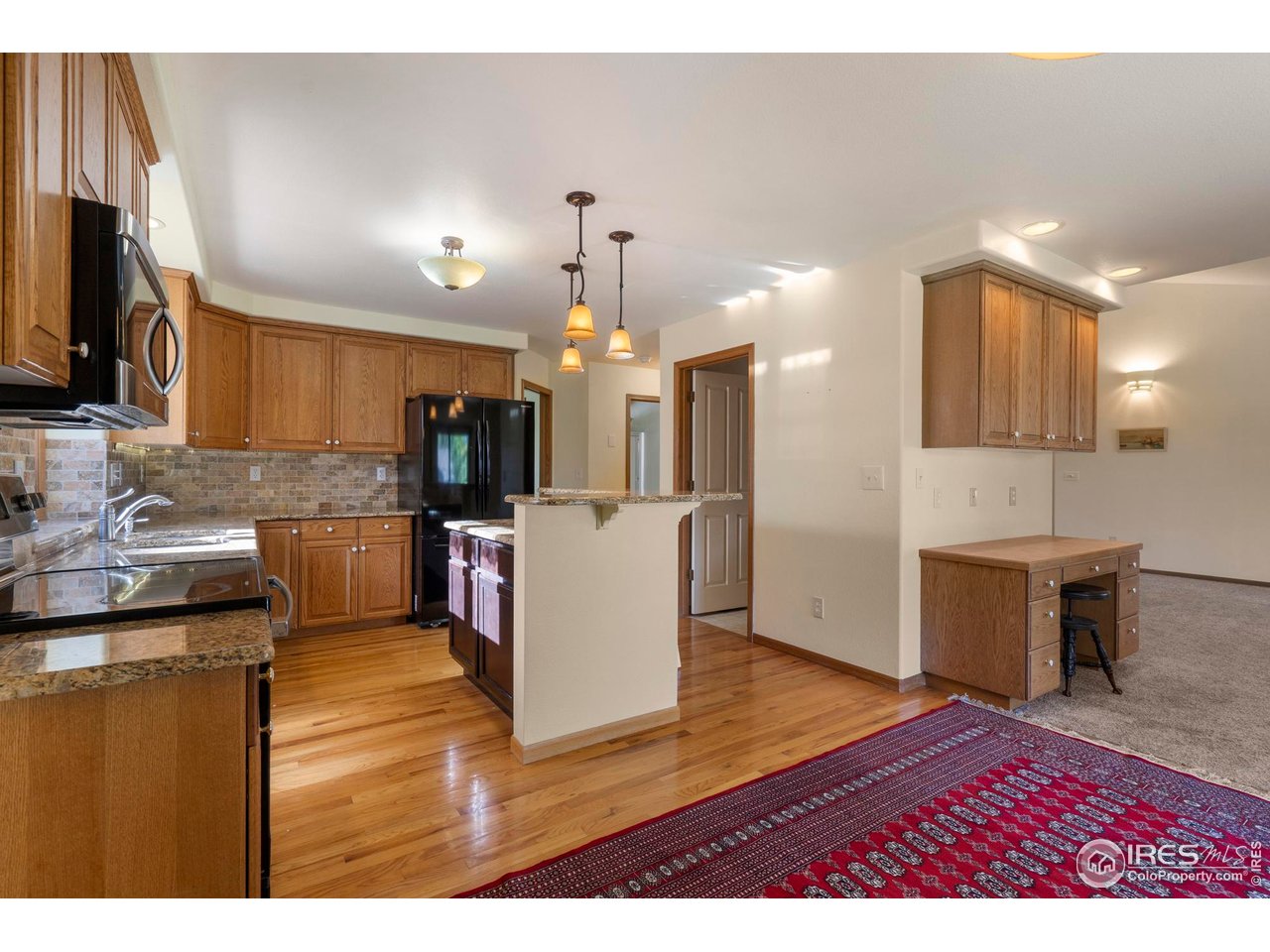 4467 West 17th Street Greeley, CO 80634 - Photo 12 of 48 a view of a kitchen with kitchen island granite countertop a stove top oven a sink dishwasher a dining table and chairs with wooden floor