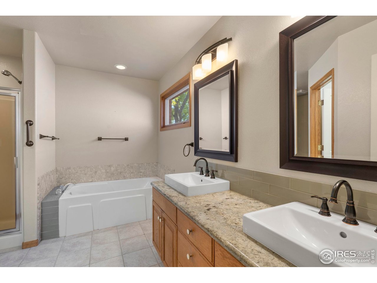 4467 West 17th Street Greeley, CO 80634 - Photo 21 of 48 a bathroom with a granite countertop sink a toilet a mirror and shower