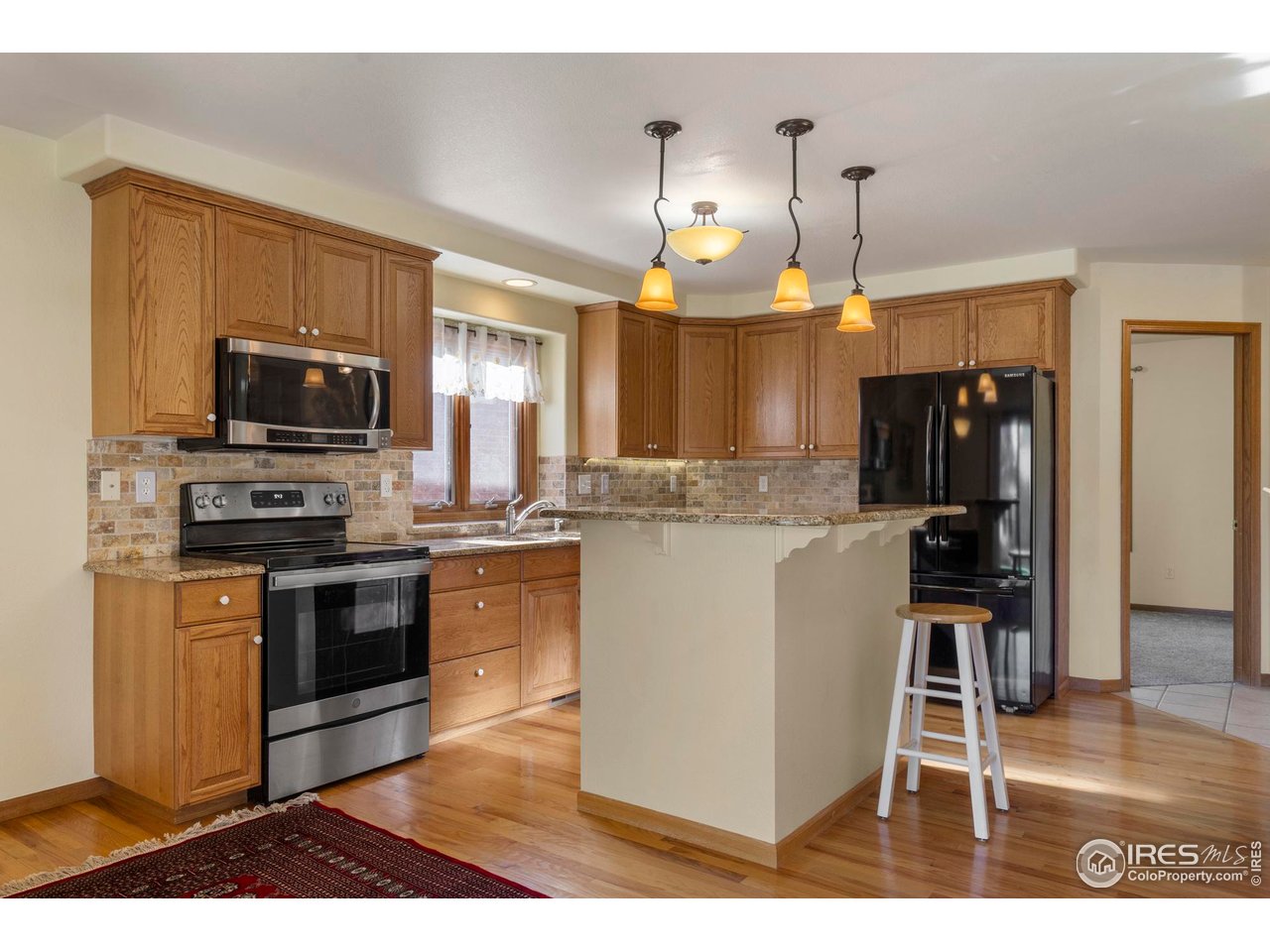 4467 West 17th Street Greeley, CO 80634 - Photo 10 of 48 a kitchen with a sink and a stove top oven with wooden floor