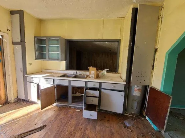 a room with stainless steel appliances kitchen island granite countertop wooden floor and a refrigerator