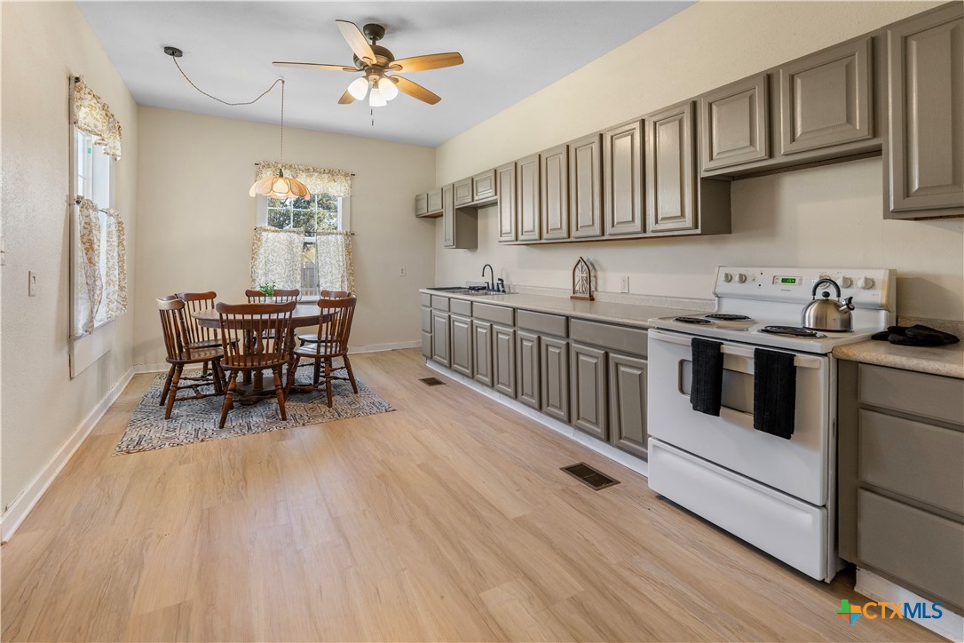 1002 East Commercial Street Victoria, TX 77901 - Photo 12 of 30 a kitchen with stainless steel appliances granite countertop a white cabinets and wooden floors
