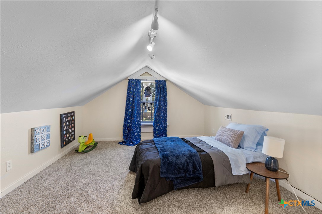 1002 East Commercial Street Victoria, TX 77901 - Photo 20 of 30 a spacious bedroom with a bed and a chandelier