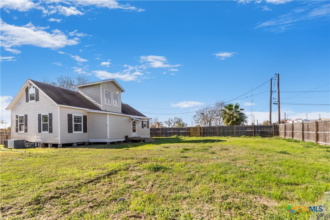 1002 East Commercial Street Victoria, TX 77901 - Photo 28 of 30 a white house with a large pool and lawn chairs under an umbrella
