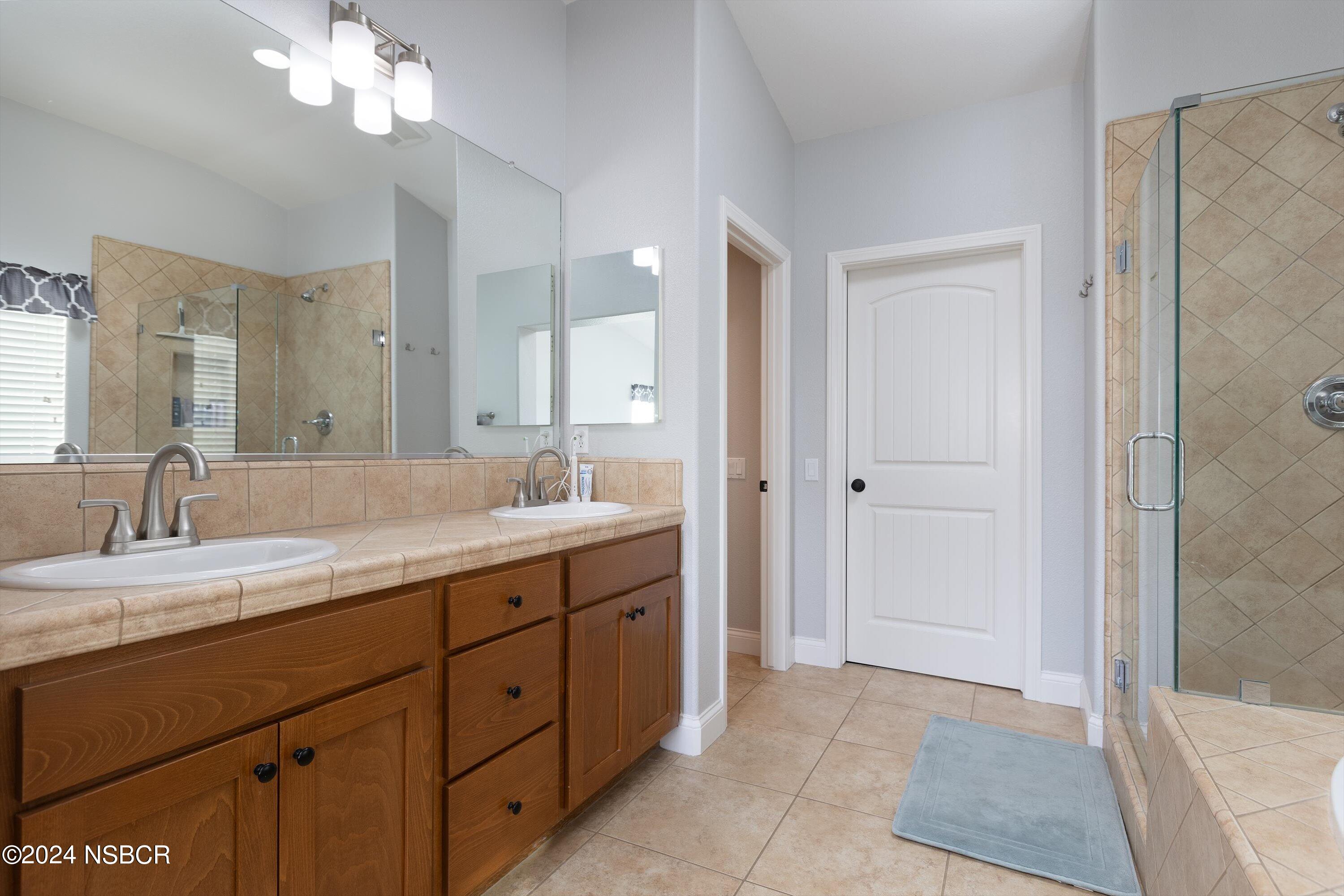 757 Pluto Avenue Lompoc, CA 93436 - Photo 14 of 41 a spacious bathroom with a granite countertop sink a mirror and a shower