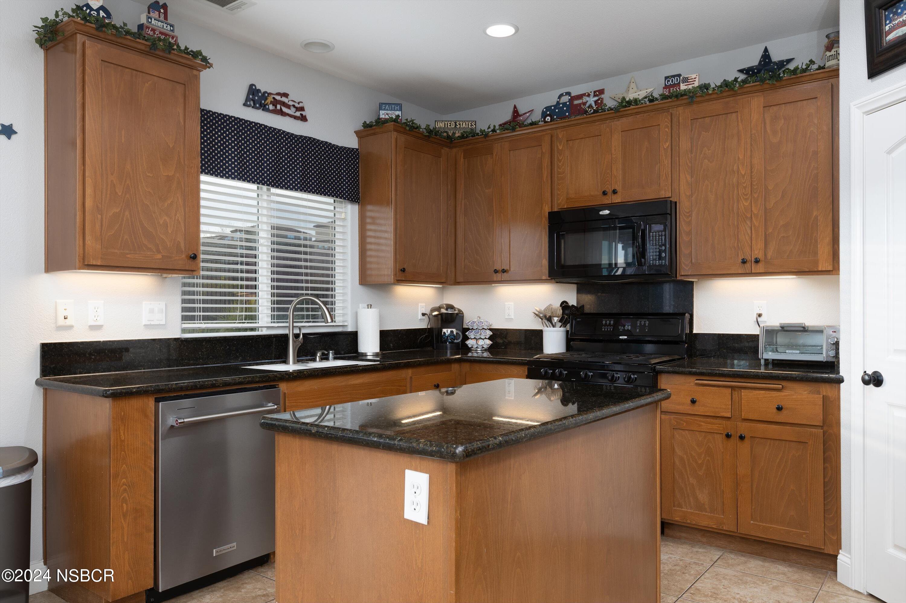 757 Pluto Avenue Lompoc, CA 93436 - Photo 8 of 41 a kitchen with granite countertop a sink a stove a microwave and wooden cabinets