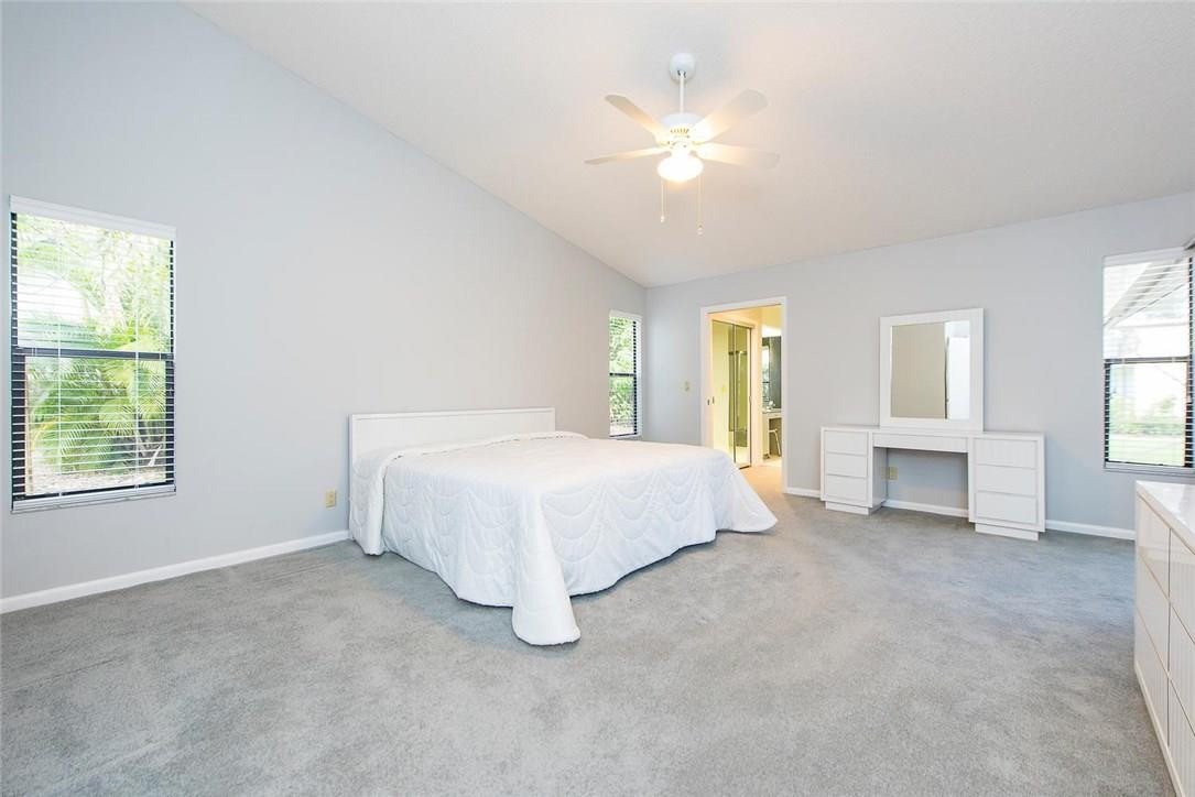 3976 Northwest 23rd Terrace Boca Raton, FL 33431 - Photo 18 of 31 a spacious bedroom with a bed and a chandelier