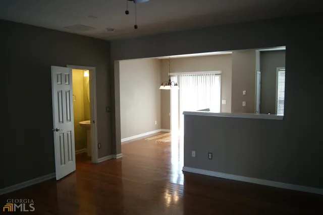 a view of a hallway with wooden floor and a bathroom