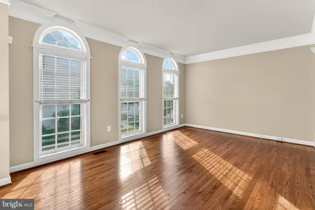 a view of an empty room with wooden floor and windows