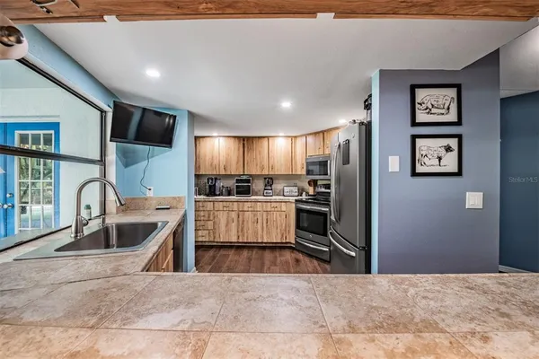 a large kitchen with stainless steel appliances kitchen island granite countertop a refrigerator and a sink