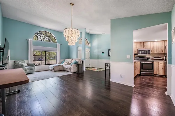 a living room with couches chandelier and kitchen view
