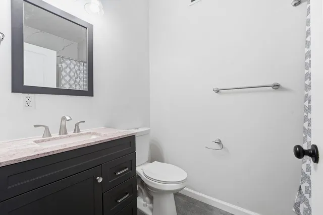 a bathroom with a granite countertop toilet sink and mirror