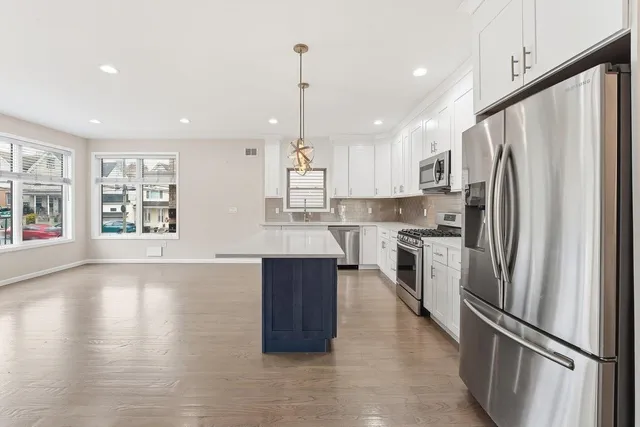 a kitchen with stainless steel appliances granite countertop a refrigerator a sink dishwasher a stove and a refrigerator with wooden floor