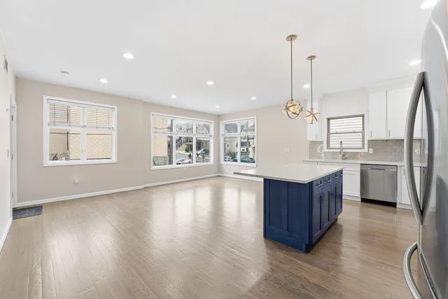 a large kitchen with stainless steel appliances kitchen island a large counter top and wooden floors